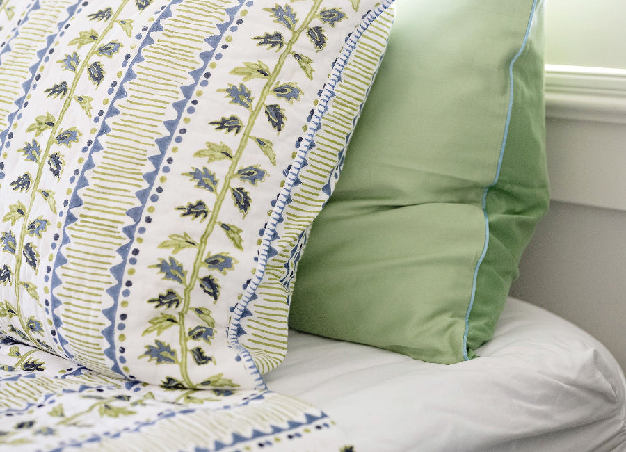 Close-up of a bed with floral-patterned bedding and green pillow