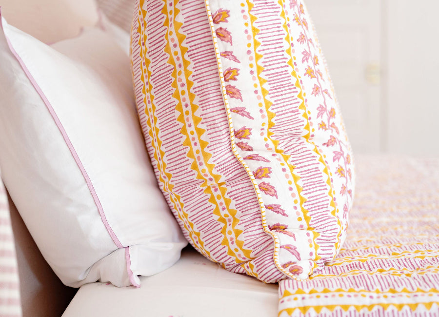 Decorative pillow with pink and yellow pattern on a white surface