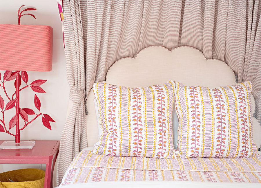 Bed with patterned bedding, pink lamp, and decorative elements in a room.