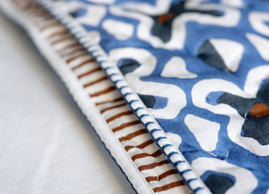 Close-up of a blue and white patterned fabric with brown border