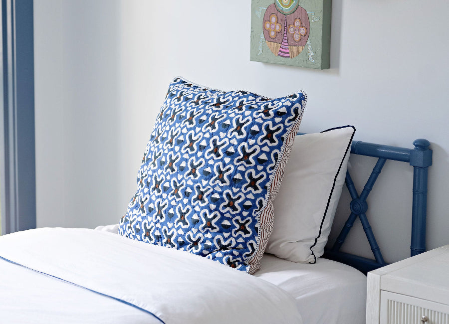Bedroom with a bed featuring patterned pillows and colorful wall art.