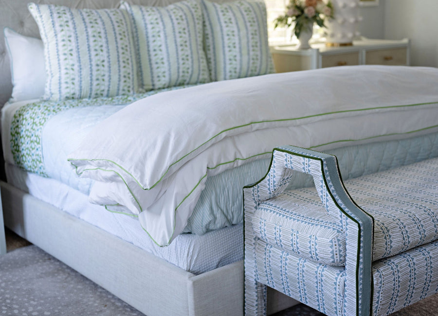 Bedroom with a bed and matching bench featuring green and white patterns.