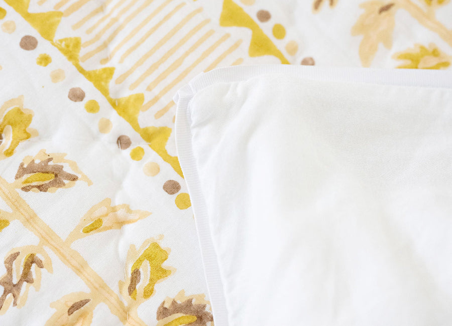 Close-up of a patterned fabric with yellow and brown designs on a white background